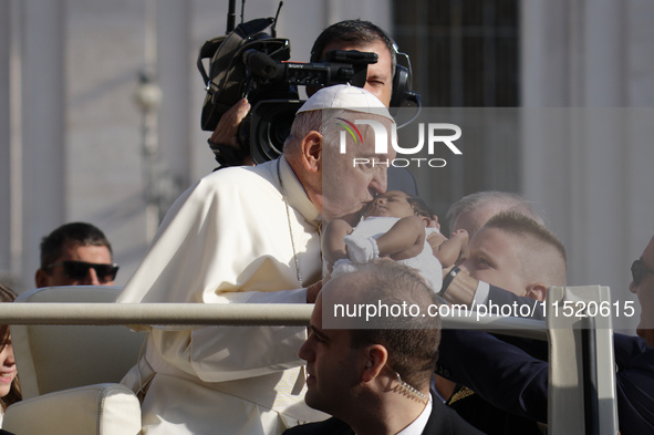 Pope Francis caresses a newborn as he arrives for his weekly General Audience in Saint Peter's Square, Vatican City, on August 28, 2024. 