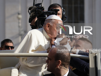 Pope Francis caresses a newborn as he arrives for his weekly General Audience in Saint Peter's Square, Vatican City, on August 28, 2024. (