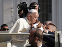 Pope Francis caresses a newborn as he arrives for his weekly General Audience in Saint Peter's Square, Vatican City, on August 28, 2024. (