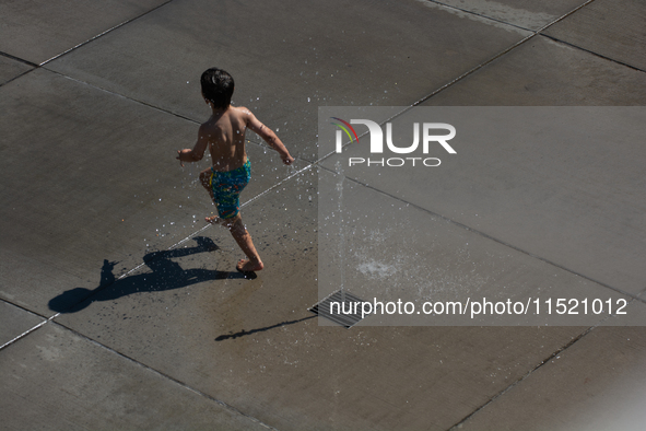 A boy plays with water from a fountain at Harry Blum Square in Cologne, Germany, on August 28, 2024. 