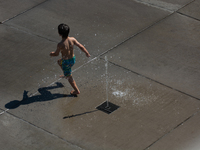 A boy plays with water from a fountain at Harry Blum Square in Cologne, Germany, on August 28, 2024. (