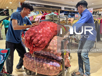 Workers move sacks of onions at a shop in Thiruvananthapuram, Kerala, India, on April 16, 2024. (