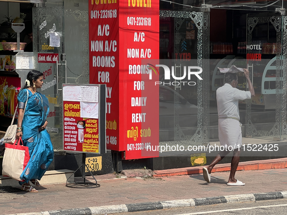 A man covers his head to protect himself from the hot sun while walking along the footpath in Thiruvananthapuram (Trivandrum), Kerala, India...