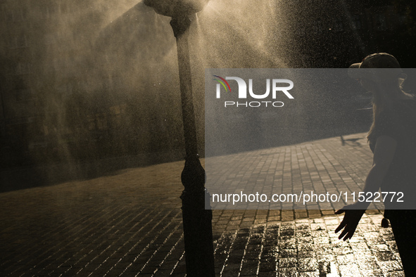 KRAKOW, POLAND - AUGUST 28:
A person cools down under the water sprinkler set up in Podgorze's Market Square as Southern Poland and Krakow e...