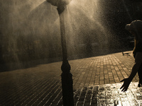 KRAKOW, POLAND - AUGUST 28:
A person cools down under the water sprinkler set up in Podgorze's Market Square as Southern Poland and Krakow e...