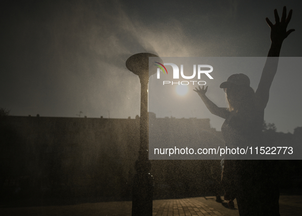 KRAKOW, POLAND - AUGUST 28:
A person cools down under the water sprinkler set up in Podgorze's Market Square as Southern Poland and Krakow e...