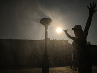 KRAKOW, POLAND - AUGUST 28:
A person cools down under the water sprinkler set up in Podgorze's Market Square as Southern Poland and Krakow e...