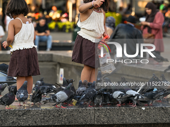 KRAKOW, POLAND - AUGUST 28:
Young visitors feed a flock of pigeons in Krakow's UNESCO Market Square as Southern Poland and Krakow endure a h...