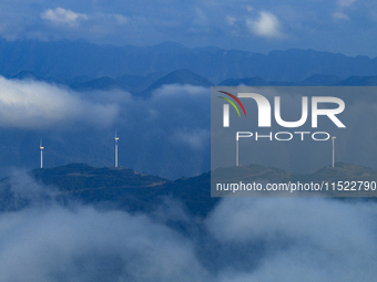 Wind turbines at a high mountain wind farm surrounded by clouds rotate against the wind in Yichang, Hubei province, China, on August 28, 202...