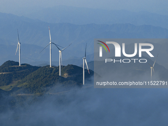 Wind turbines at a high mountain wind farm surrounded by clouds rotate against the wind in Yichang, Hubei province, China, on August 28, 202...