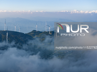 Wind turbines at a high mountain wind farm surrounded by clouds rotate against the wind in Yichang, Hubei province, China, on August 28, 202...