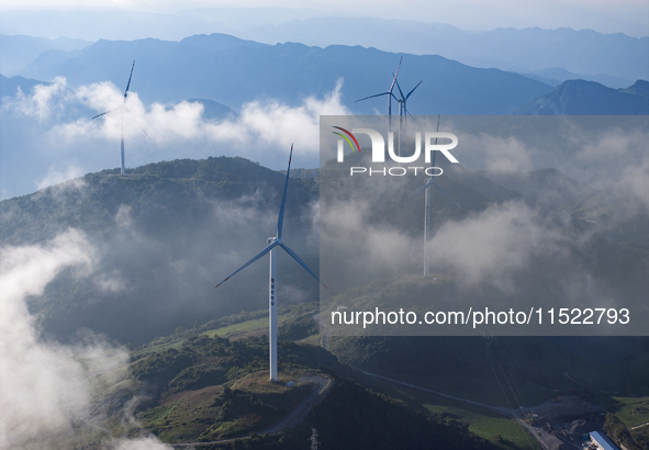 Wind turbines at a high mountain wind farm surrounded by clouds rotate against the wind in Yichang, Hubei province, China, on August 28, 202...