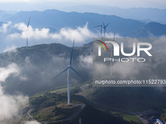 Wind turbines at a high mountain wind farm surrounded by clouds rotate against the wind in Yichang, Hubei province, China, on August 28, 202...