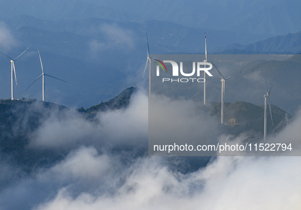 Wind turbines at a high mountain wind farm surrounded by clouds rotate against the wind in Yichang, Hubei province, China, on August 28, 202...