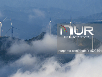 Wind turbines at a high mountain wind farm surrounded by clouds rotate against the wind in Yichang, Hubei province, China, on August 28, 202...