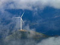 Wind turbines at a high mountain wind farm surrounded by clouds rotate against the wind in Yichang, Hubei province, China, on August 28, 202...