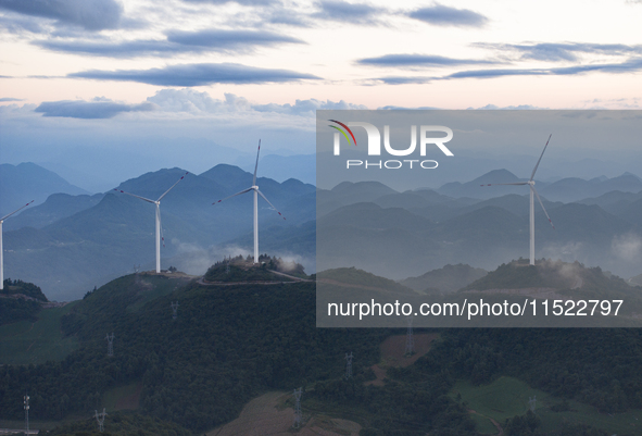 Wind turbines at a high mountain wind farm surrounded by clouds rotate against the wind in Yichang, Hubei province, China, on August 28, 202...