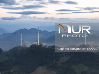 Wind turbines at a high mountain wind farm surrounded by clouds rotate against the wind in Yichang, Hubei province, China, on August 28, 202...