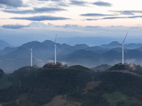 Wind turbines at a high mountain wind farm surrounded by clouds rotate against the wind in Yichang, Hubei province, China, on August 28, 202...