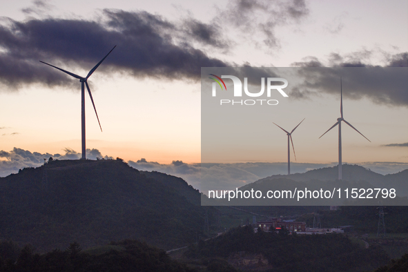 Wind turbines at a high mountain wind farm surrounded by clouds rotate against the wind in Yichang, Hubei province, China, on August 28, 202...