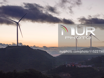 Wind turbines at a high mountain wind farm surrounded by clouds rotate against the wind in Yichang, Hubei province, China, on August 28, 202...