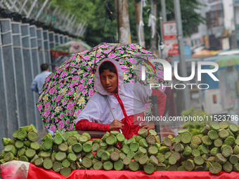 A boy holds an umbrella while waiting for customers as it rains in Srinagar, Jammu and Kashmir, on August 29, 2024. (