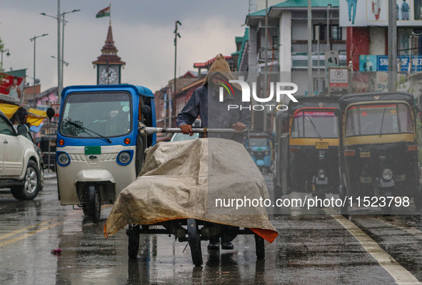 A man pushes a handcart as it rains in Srinagar, Jammu and Kashmir, on August 29, 2024. 