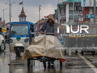 A man pushes a handcart as it rains in Srinagar, Jammu and Kashmir, on August 29, 2024. (