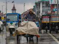 A man pushes a handcart as it rains in Srinagar, Jammu and Kashmir, on August 29, 2024. (