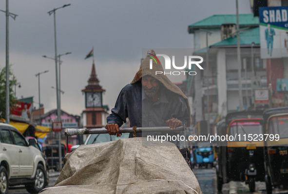 A man pushes a handcart as it rains in Srinagar, Jammu and Kashmir, on August 29, 2024. 