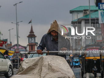 A man pushes a handcart as it rains in Srinagar, Jammu and Kashmir, on August 29, 2024. (