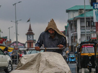 A man pushes a handcart as it rains in Srinagar, Jammu and Kashmir, on August 29, 2024. (