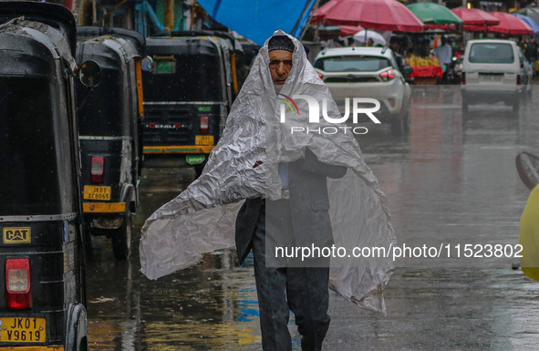 A man covers himself with a polythene sheet as it rains in Srinagar, Jammu and Kashmir, on August 29, 2024. 