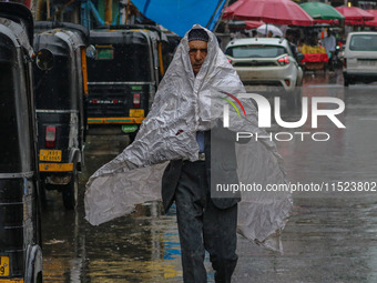 A man covers himself with a polythene sheet as it rains in Srinagar, Jammu and Kashmir, on August 29, 2024. (