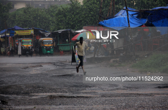 Pedestrians and commuters are seen on the road as it rains in Bhubaneswar, the capital city of the eastern Indian state of Odisha. Rain lash...