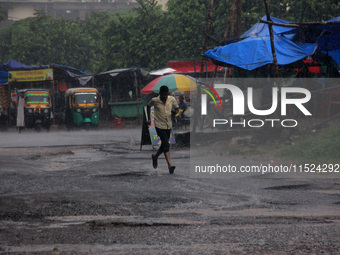 Pedestrians and commuters are seen on the road as it rains in Bhubaneswar, the capital city of the eastern Indian state of Odisha. Rain lash...