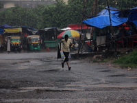 Pedestrians and commuters are seen on the road as it rains in Bhubaneswar, the capital city of the eastern Indian state of Odisha. Rain lash...