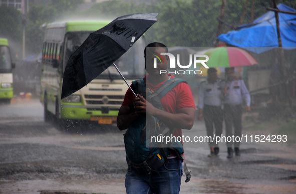 Pedestrians and commuters are seen on the road as it rains in Bhubaneswar, the capital city of the eastern Indian state of Odisha. Rain lash...