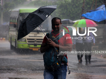 Pedestrians and commuters are seen on the road as it rains in Bhubaneswar, the capital city of the eastern Indian state of Odisha. Rain lash...