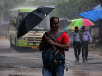 Pedestrians and commuters are seen on the road as it rains in Bhubaneswar, the capital city of the eastern Indian state of Odisha. Rain lash...