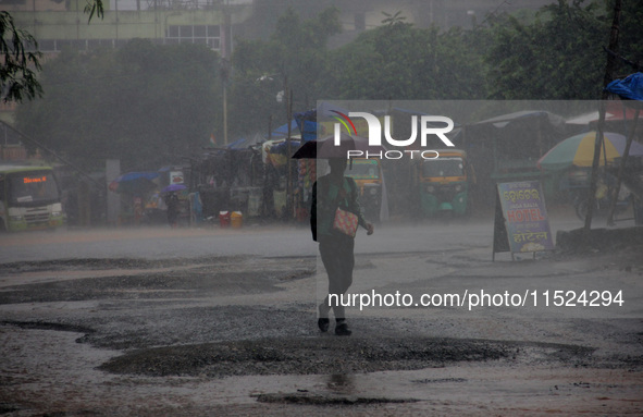 Pedestrians and commuters are seen on the road as it rains in Bhubaneswar, the capital city of the eastern Indian state of Odisha. Rain lash...