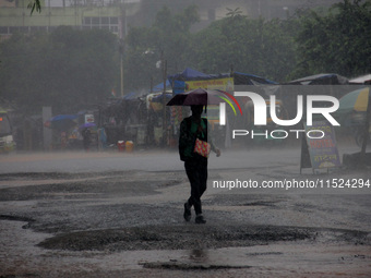 Pedestrians and commuters are seen on the road as it rains in Bhubaneswar, the capital city of the eastern Indian state of Odisha. Rain lash...