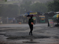 Pedestrians and commuters are seen on the road as it rains in Bhubaneswar, the capital city of the eastern Indian state of Odisha. Rain lash...