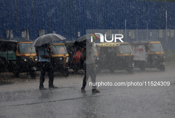 Pedestrians and commuters are seen on the road as it rains in Bhubaneswar, the capital city of the eastern Indian state of Odisha. Rain lash...