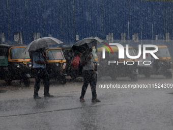 Pedestrians and commuters are seen on the road as it rains in Bhubaneswar, the capital city of the eastern Indian state of Odisha. Rain lash...