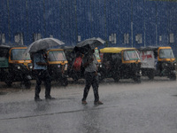 Pedestrians and commuters are seen on the road as it rains in Bhubaneswar, the capital city of the eastern Indian state of Odisha. Rain lash...