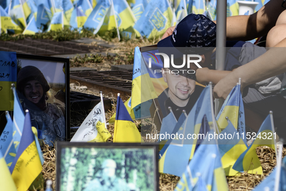 A child kisses a portrait of his father at a makeshift memorial for fallen Ukrainian soldiers on the Day of Remembrance of Ukraine's Defende...