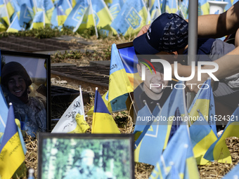 A child kisses a portrait of his father at a makeshift memorial for fallen Ukrainian soldiers on the Day of Remembrance of Ukraine's Defende...