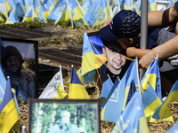 A child kisses a portrait of his father at a makeshift memorial for fallen Ukrainian soldiers on the Day of Remembrance of Ukraine's Defende...