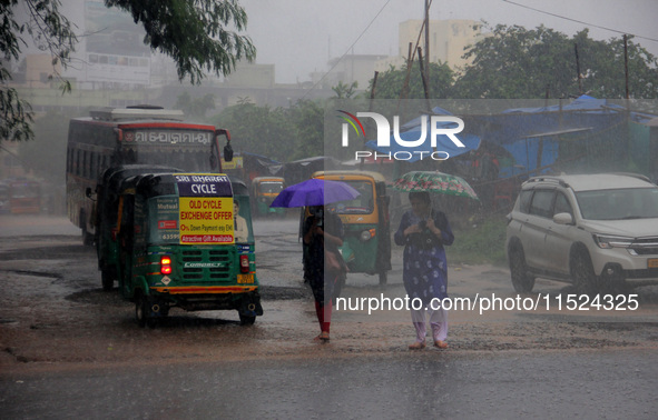 Pedestrians and commuters are seen on the road as it rains in Bhubaneswar, the capital city of the eastern Indian state of Odisha. Rain lash...